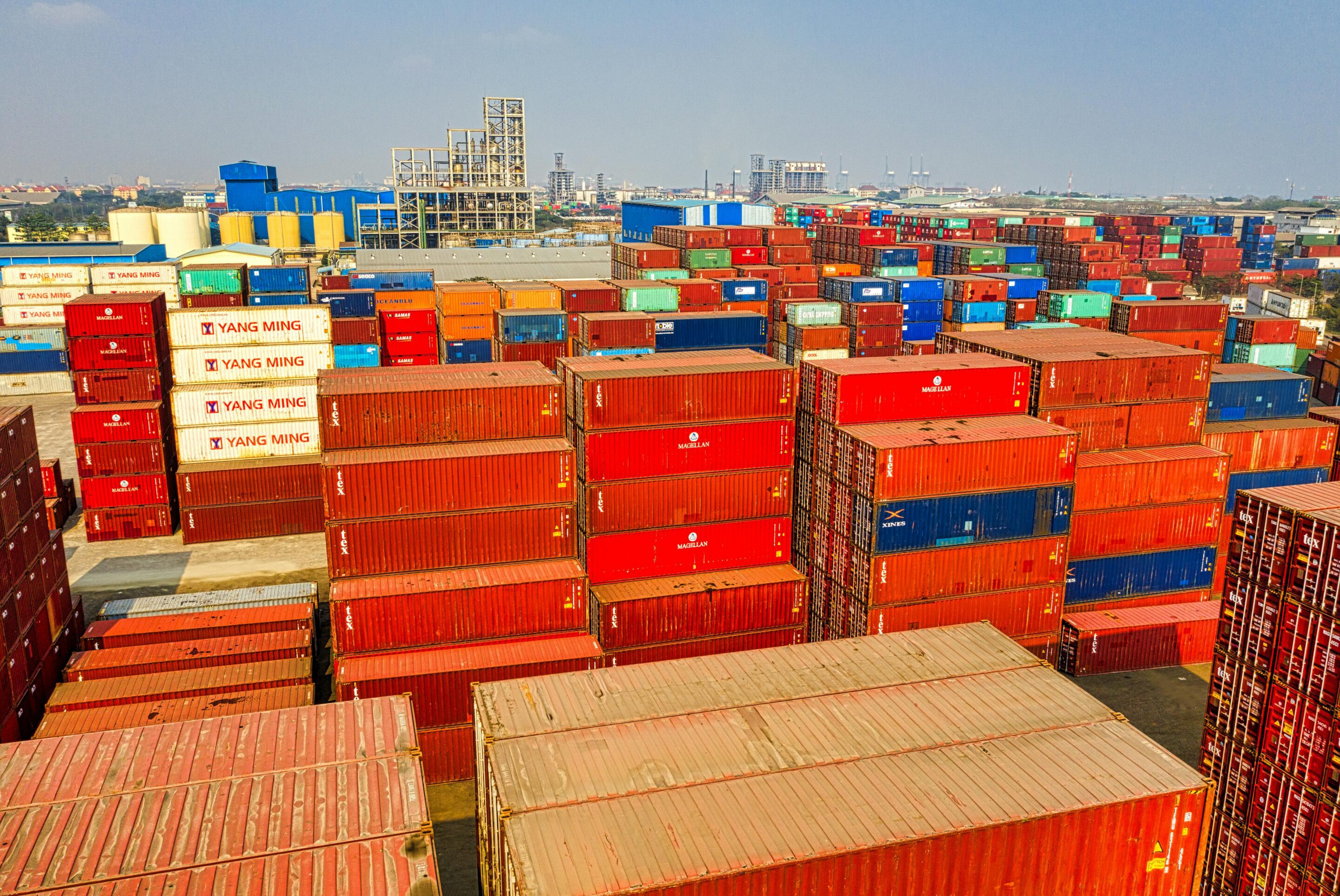 Colorful cargo containers stacked at a busy logistics yard.