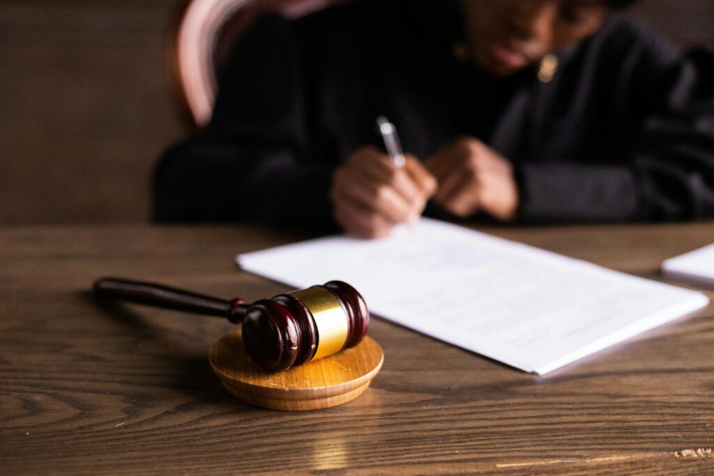 Gavel resting on desk with a judge signing legal documents in the background.