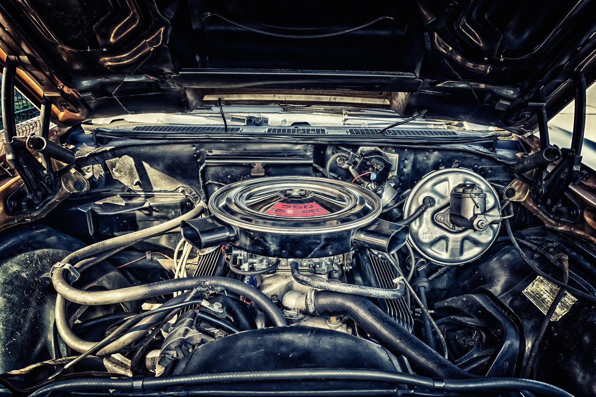 Vintage car engine bay with a chrome air filter and 350 Turbo-Fire V8 decal.