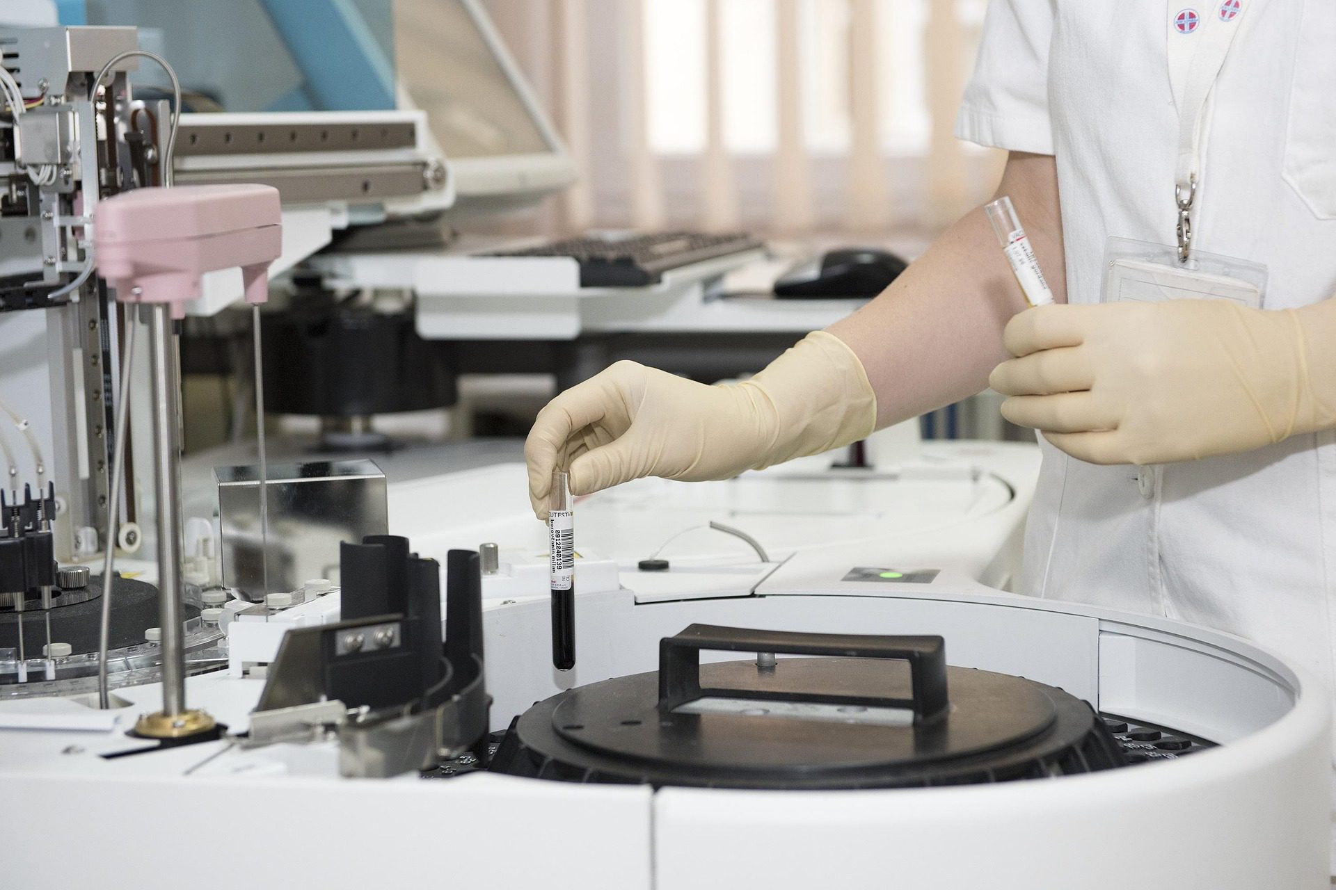 Lab technician placing a blood sample into an automated analyzer.