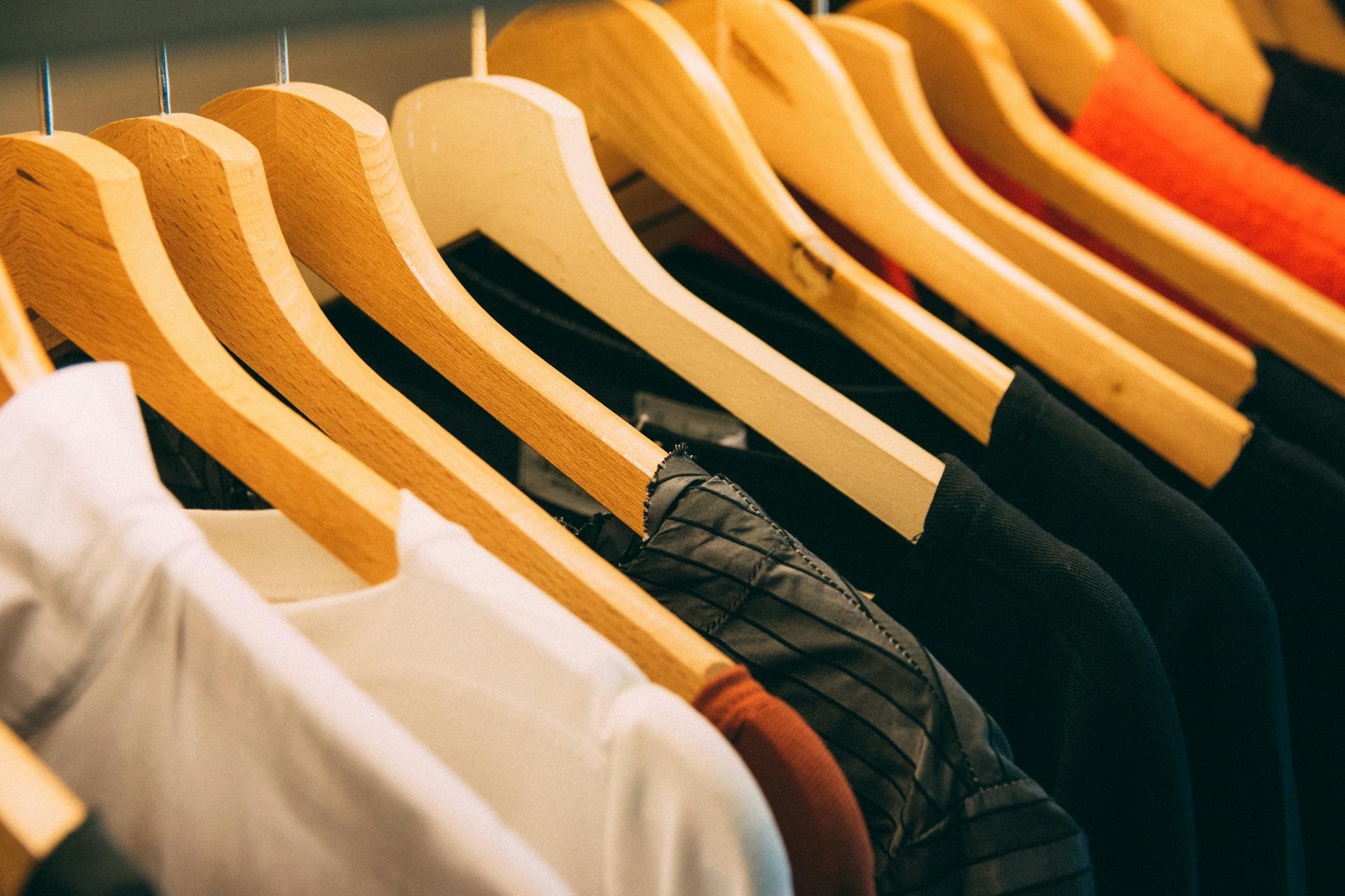 Close-up of clothing on wooden hangers in a retail store.