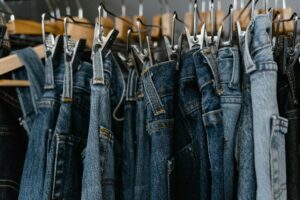 Close-up of various denim jeans hanging on clip hangers.