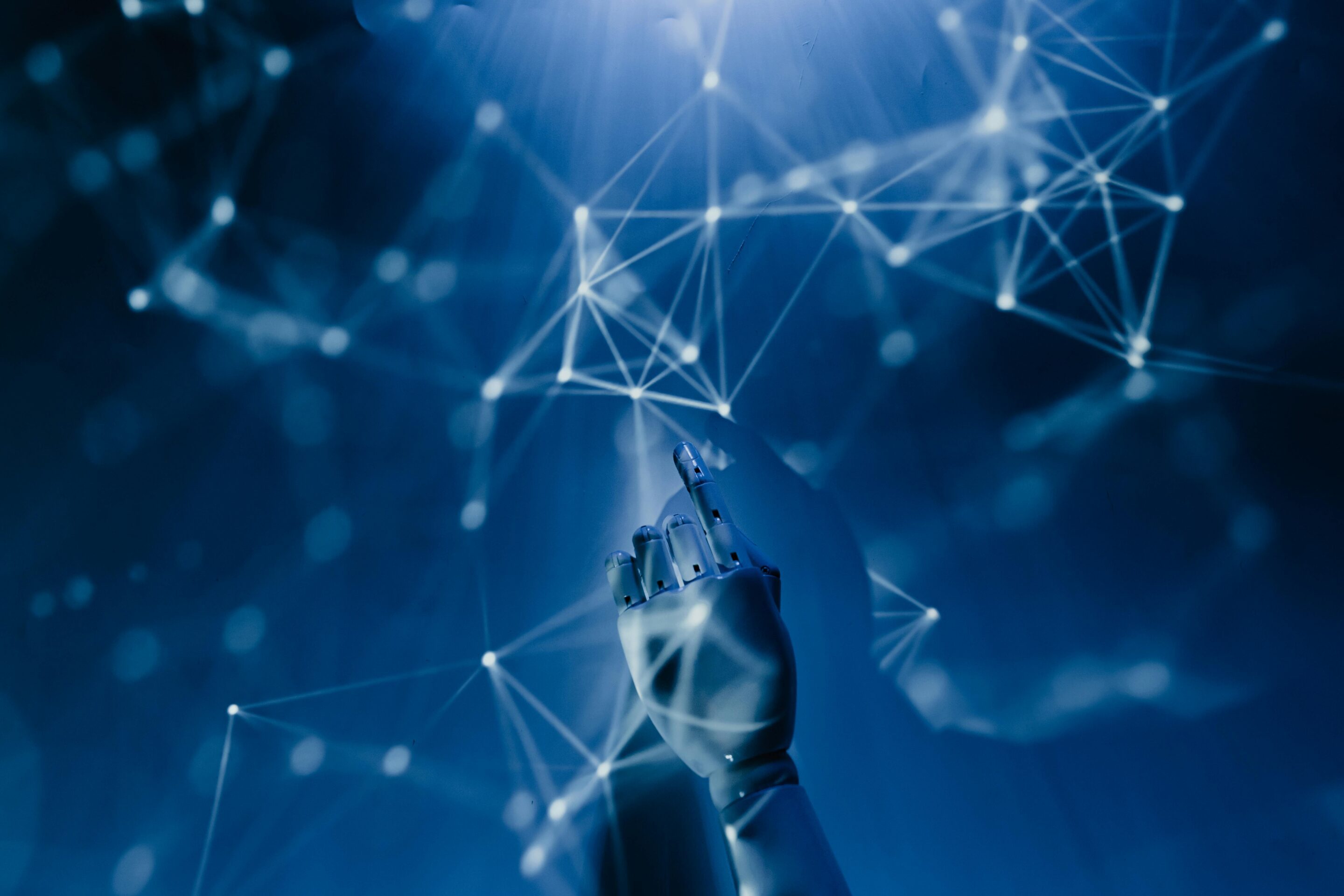 A robotic hand pointing toward a glowing blue digital network.